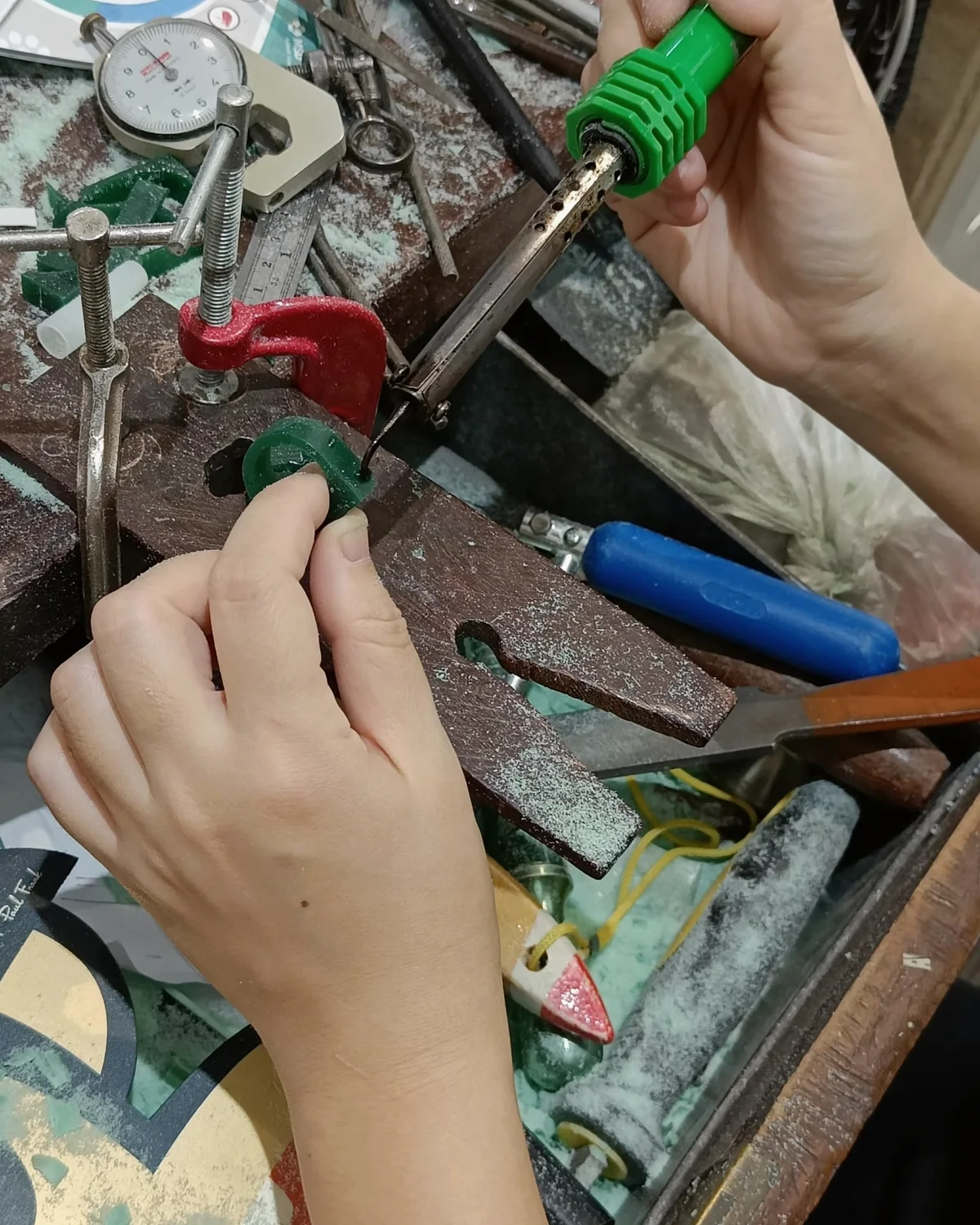 Hands shaping a jewellery component at a workbench